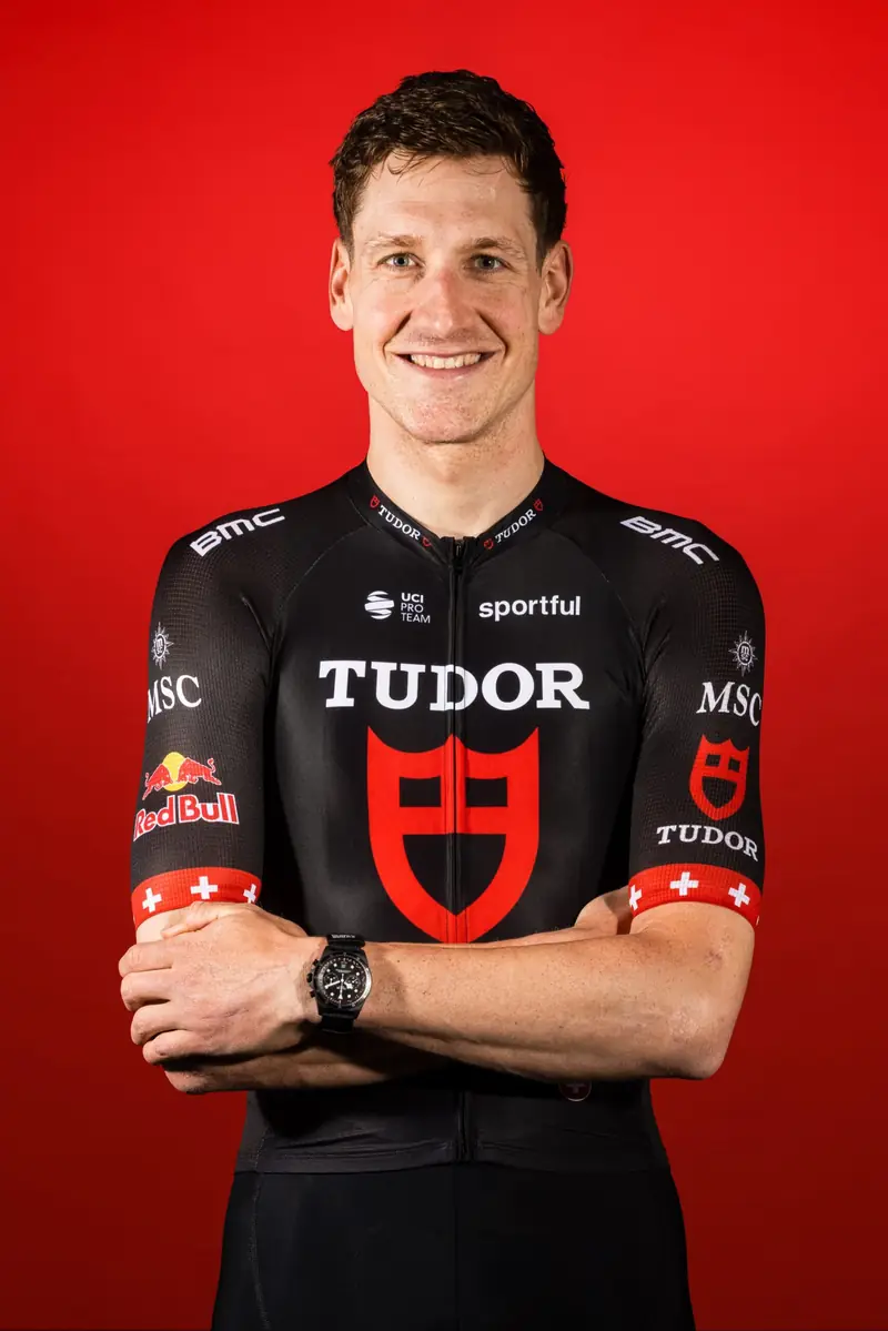 Porträt von Stefan Küng im Tudor-Trikot vor rotem Hintergrund