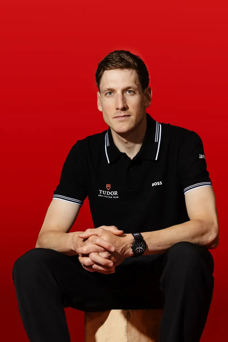 Porträt von Stefan Küng im schwarzen Teampolo vor rotem Hintergrund